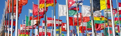 A photo of many flags of the world flapping in wind at the top of their masts